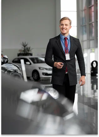 Esta é uma fotografia de um homem que se encontra no interior de um concessionário automóvel moderno ou de um centro automóvel.