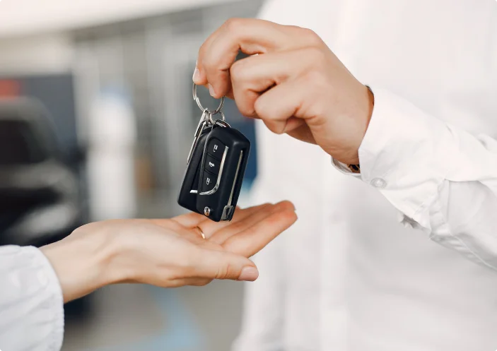 Na fotografia, vê-se uma mulher adulta e um jovem ou um homem na rua, provavelmente junto a um concessionário automóvel ou a um parque de estacionamento.